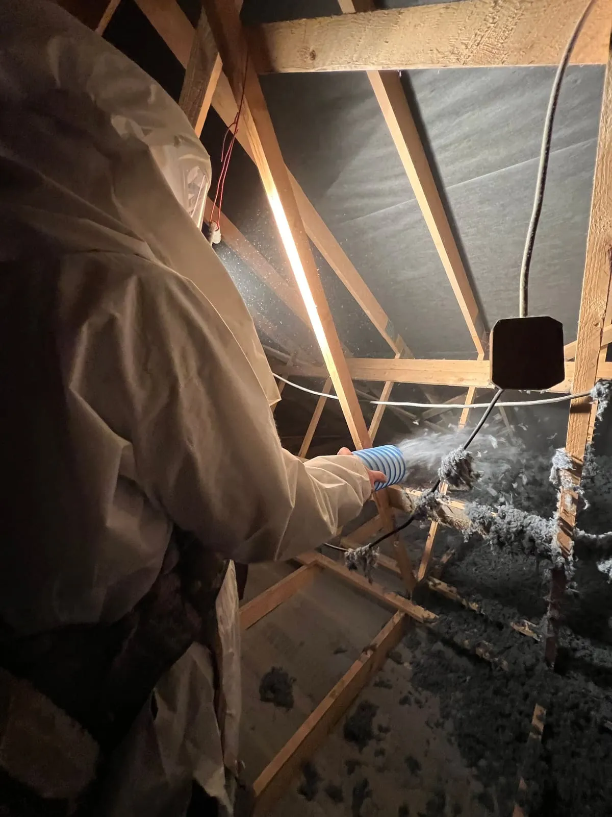 Applicateur Isolatech en plein soufflage de laine de coton dans les combles, charpente bois apparente · Saint-Barthélemy (70200, près de Lure, Haute-Saône) · Isolatech